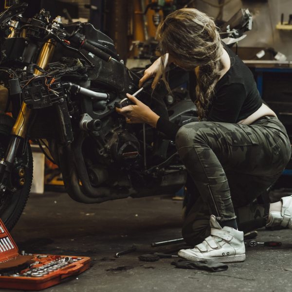 beautiful girl with long hair in the garage repairing a motorcycle